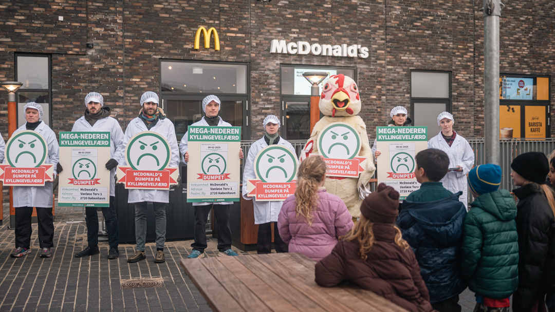 Børnehavebørn kigger nysgerrigt på aktionen foran McDonald's nye restaurant, hvor der vises skilte med sure smileyer i protest.